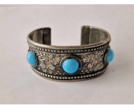 A wide silver bangle with three turquoise stones
