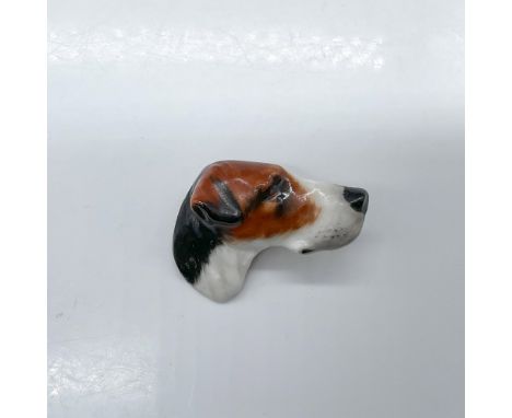 Pottery pin molded as a hound head; needle pin fasten. White, brown and black coloration. Royal Doulton impressed stamp. Issu