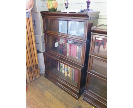 A Globe Wernicke oak graduated three tier stacking bookcase, with glazed fall fronts and base drawer 86cm wide, 131cm high 
