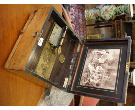 A walnut cased 9 1/2 inch polyphon, with Schutze Marke medallion, the white resin inlaid lid with scene of putti playing inst