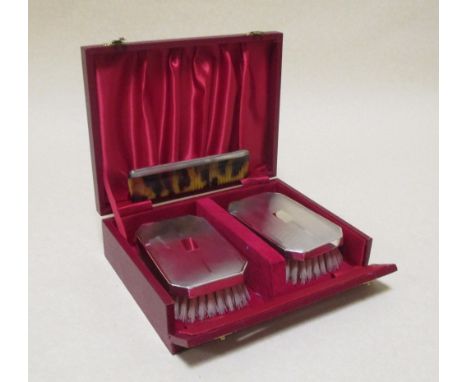 A cased pair of silver backed hair brushes and a comb 