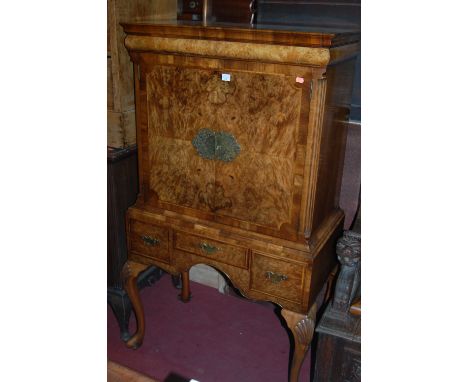 A walnut and figured walnut crossbanded and further feather banded former cocktail cabinet, raised on integral stand with thr