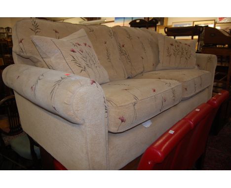 A modern cream floral upholstered three-seater sofa on turned supports 