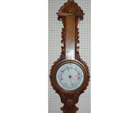 An early 20th century carved oak aneroid two dial wheel barometer (thermometer scale missing)