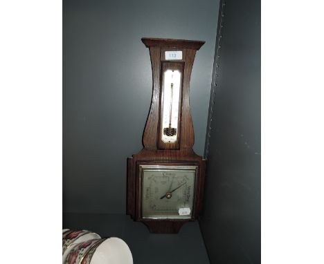 A wall mounted barometer with oak case