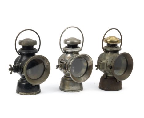 Three Lucas oil-illuminating side-lamps,comprising two fork-mounted No.721 and No.722 lamps, one Japanned black and converted