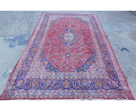 A large Persian carpet, of rectangular form, set with a geometric floral pattern, with an outer field set with further flower