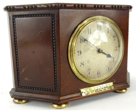 An early 20thC mahogany cased mantel clock, in shaped case, with upper beading on compressed orb feet, fronted by a plaque re