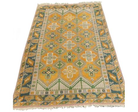 A Turkish carpet, with an overall design of stylised stars, lozenges, etc., in green and pale blue on a yellow ground with on