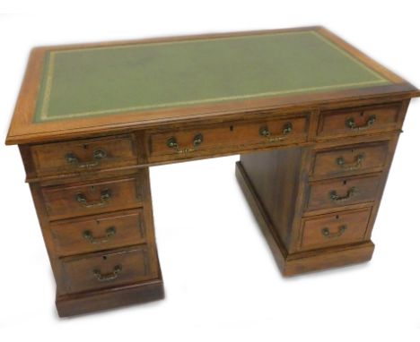 A late 19th/early 20thC oak pedestal desk, the rectangular top with a green tooled leather insert above an arrangement of nin