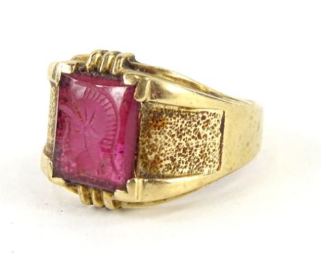 A 9ct gold dress ring, claw set with a rectangular pink coloured seal stone, set with a figure quarter profile on a textured 