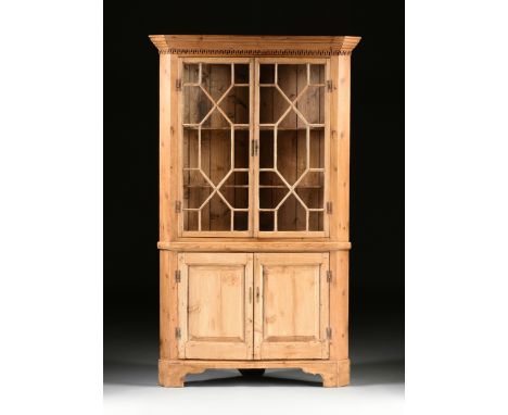 A GEORGE III STYLE WAXED PINE CORNER BOOKCASE CABINET, with a tapering molded cornice above an applied stylized Greek key fri