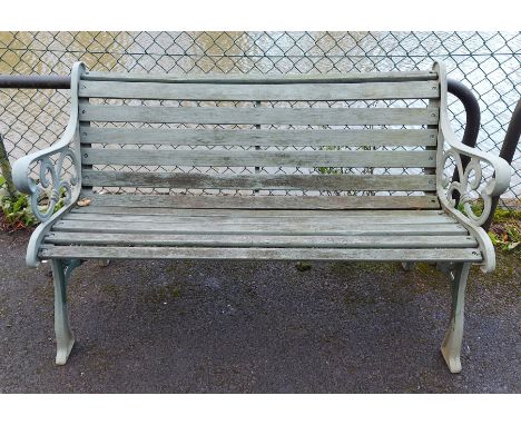 A green painted cast-iron &amp; wooden slatted garden bench on pierced &amp; shaped end supports, 50¾” long.