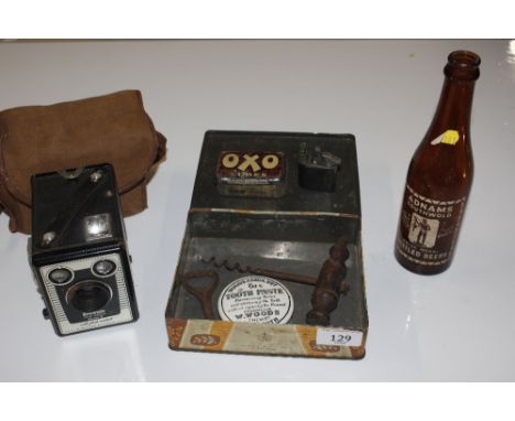 A Kodak box camera; a Adnams Southwold beer bottle; and a tin containing cigarette lighter, corkscrew, paste pot lid and Oxo 