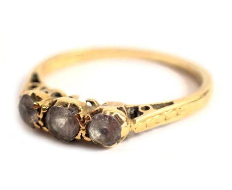 A diamond three stone dress ring, set with three tiny diamonds in raised claw basket setting, on yellow metal band stamped 75