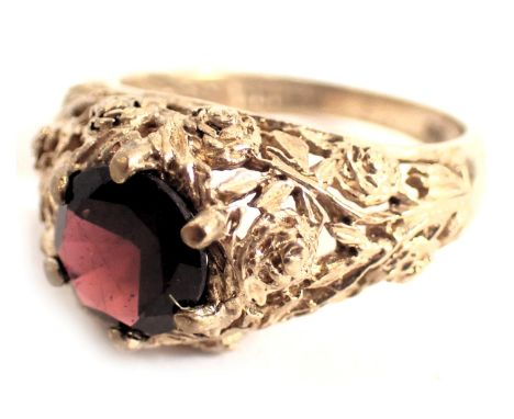 A 9ct gold garnet dress ring, the round brilliant cut garnet in six claw setting, with scroll rose design mount and shoulders