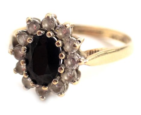 A 9ct gold cluster ring, the oval cluster centred by a dark blue stone surrounded by CZ's, in a raised claw basket setting, r