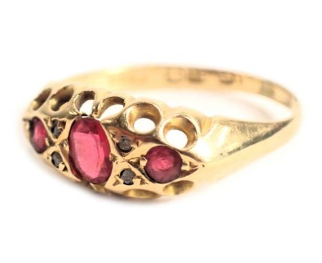 An 18ct gold gypsy ring, set with three oval cut rubies and four tiny diamonds, with pierced work border, ring size O, 2.2g a