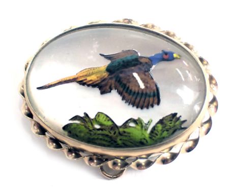 A partridge painted oval brooch, touched up with enamel decoration, on mother of pearl back, in yellow metal frame with rope 