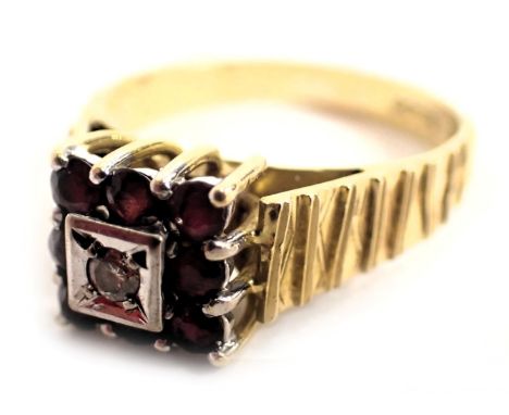 A 9ct gold dress ring, the square set panel with eight rubies, in claw setting with central tiny diamond in illusion platinum