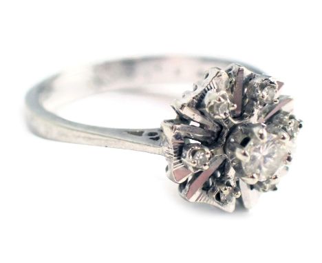 A diamond cluster ring, the petalated flower set with tiny diamonds and a central round brilliant cut raised diamond approx 0