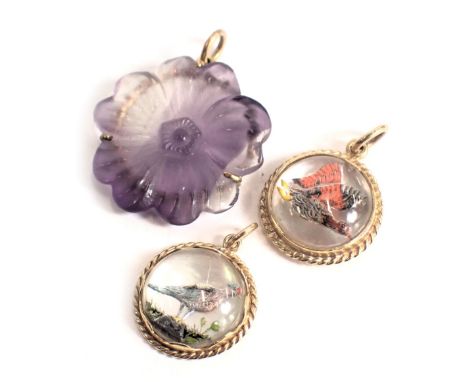 Three pendants, comprising a purple glass flower pendant and plated frame, and two mother of pearl backed bird pendants, yell