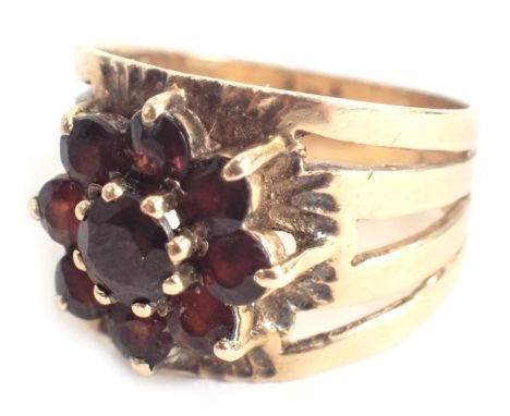 A garnet cluster ring, the garnet cluster in claw setting, with hammered and etched design ring head, on four splayed shoulde