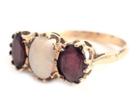 A 9ct gold dress ring, set with two garnets and an opal, each oval cut, in raised claw basket setting, ring size Q, 3.2g all 