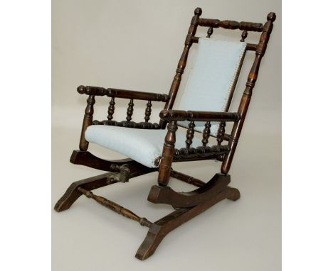 An Edwardian beech bobbin turned childs rocking chair armchair with sky blue upholstered back and overstuffed seat
