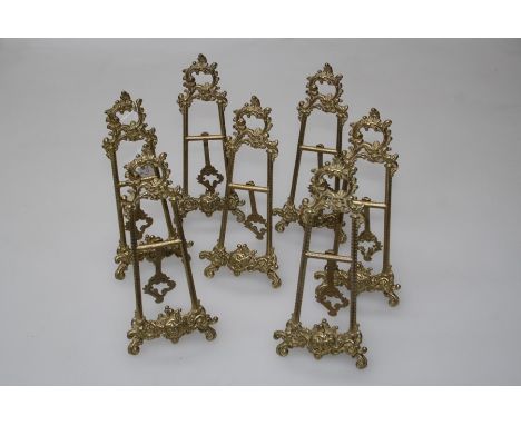 A set of seven brass ceramic stands in the form of easels in the rococo taste, height 25cm