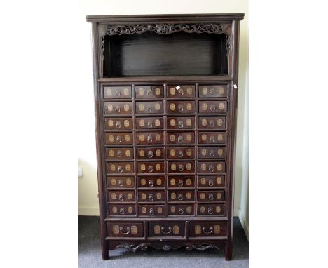 An antique Chinese hardwood apothecary chest, the rectangular top over pierced frieze, shelf and an arrangement of thirty nin