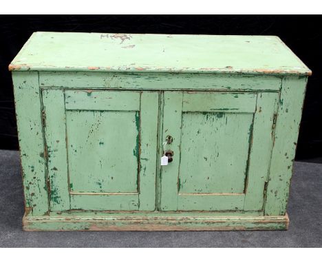 A 19th century green painted pine low cupboard, the rectangular top above a pair of panel doors enclosing single shelf, on pl