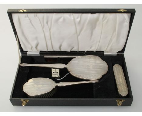 A four piece cased silver mounted mirror and brush suite, each with engine turned decoration and M monogram. Birmingham 1972