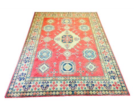 KAZAK CARPET, 308cm x 215cm, central medallion on a ruby field of scattered amulates within corresponding bands and borders.