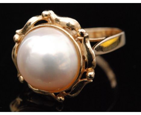 A 14ct mabe pearl ring, collar set pearl within a pierced foliate border to high basket mount and plain band stamped, ring si