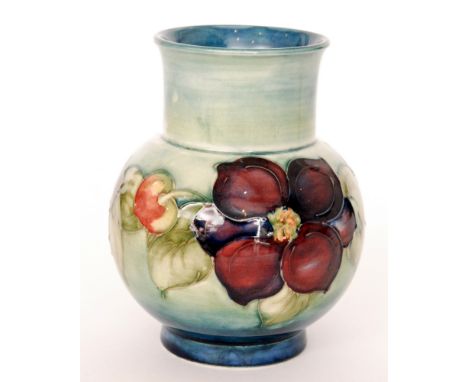 A Moorcroft vase of footed globe and shaft form decorated in the Clematis pattern with a band of flowers and foliage against 