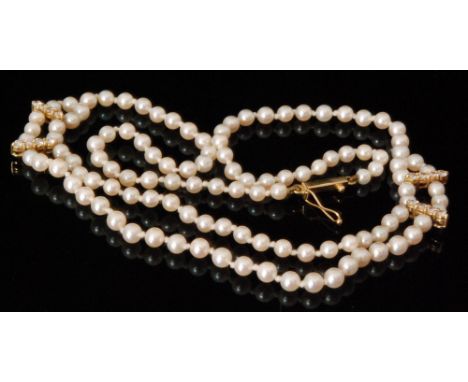 A cultured pearl necklet designed as a double row of pearls with four 18ct diamond set spacers tapering to a single row of pe