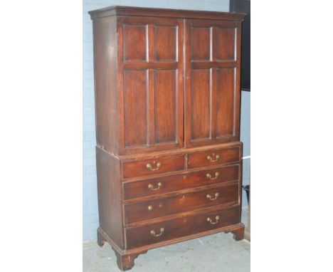 An early 19th Century mahogany press cupboard, the hanging space enclosed by a pair of panelled doors over a base fitted with