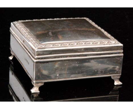 An Edwardian hallmarked silver square jewellery box, the hinged lid with cast border decoration opening to reveal a blue velv