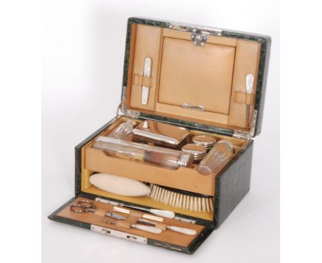 An early 20th Century green stained crocodile dressing case fitted with plated top jars, brushes and tools, by H.Greaves, New
