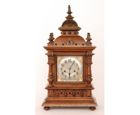 A late 19th Century walnut cased mantle clock, the silvered square dial enclosed by a pillared glazed case on stepped plinth 