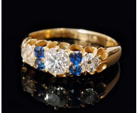 A hallmarked 18ct sapphire and diamond ring, three graduated old brilliant cut diamonds spaced by two pairs of cushion cut sa