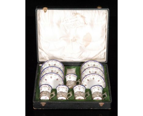 A boxed Royal Worcester coffee set comprising six saucers and five cans each within hallmarked silver holders decorated with 