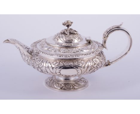 A George IV silver teapot, by William Hewitt, London 1825, of compressed circular and pedestal form, embossed and repousse fl