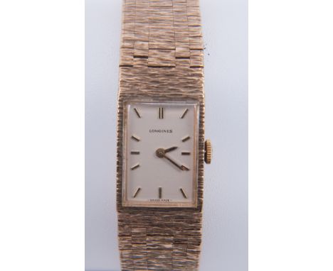 Longines - a lady's 9 carat yellow gold bracelet watch, having a rectangular cream baton dial, in a 9 carat yellow gold case 