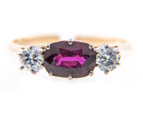A ruby and diamond three stone ring, an oval mixed cut ruby  6.2mm x 8.8mm, four claw set horizontally with a brilliant cut d