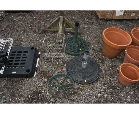 A wrought iron planter; a cast iron wheel and two parasol bases