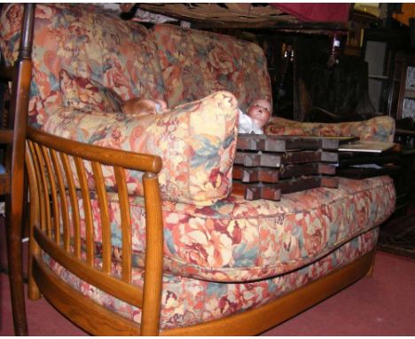 An Ercol elm two seater sofa with floral cushions