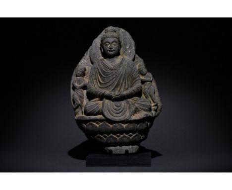 100-300 AD. Gandharan. A grey schist figure of a seated Buddha. He is depicted wearing a flowing robe and a topknot (ushnisha