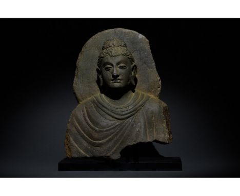 100-300 AD. Gandharan. A grey schist torso of a Buddha. He is depicted wearing a flowing robe and a topknot (ushnisha). He is